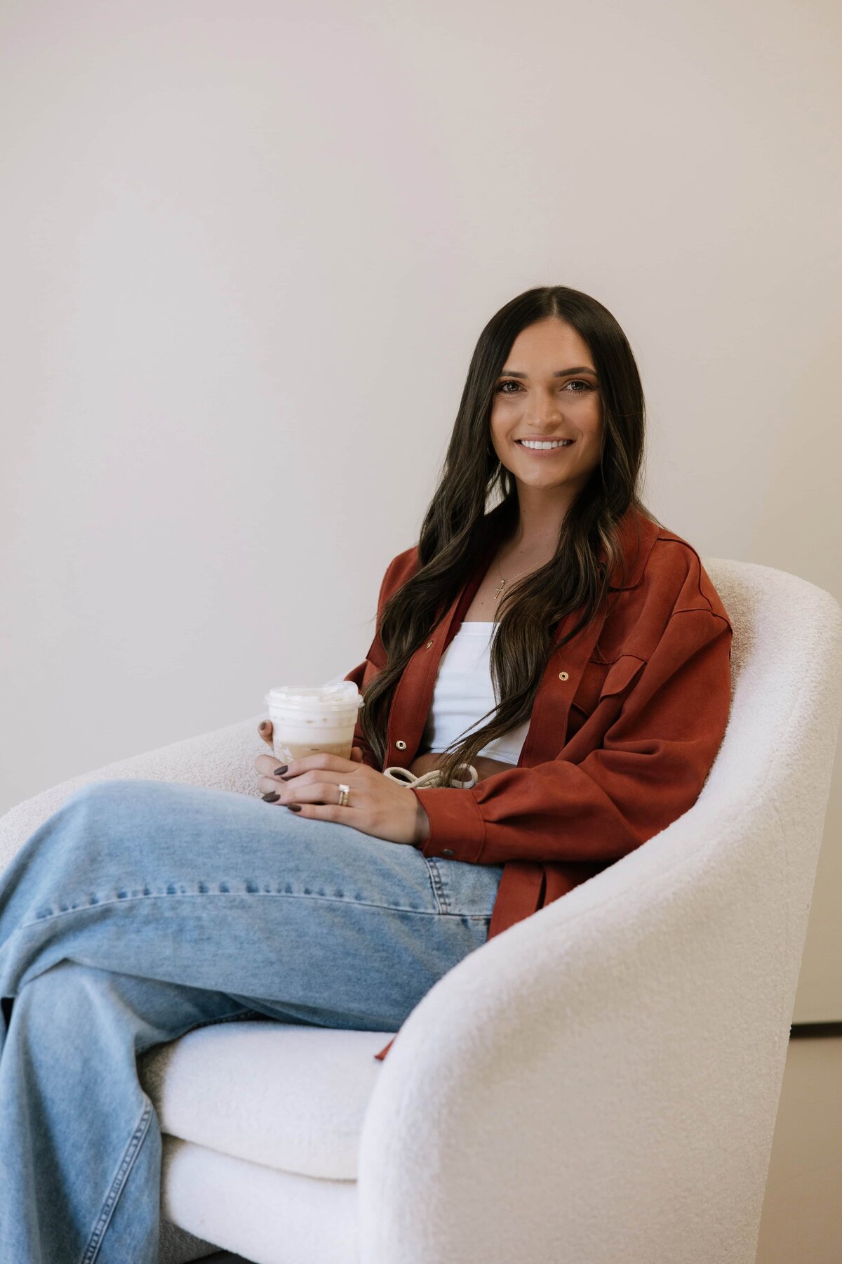 A health coach holds a coffee and smiles at the camera.