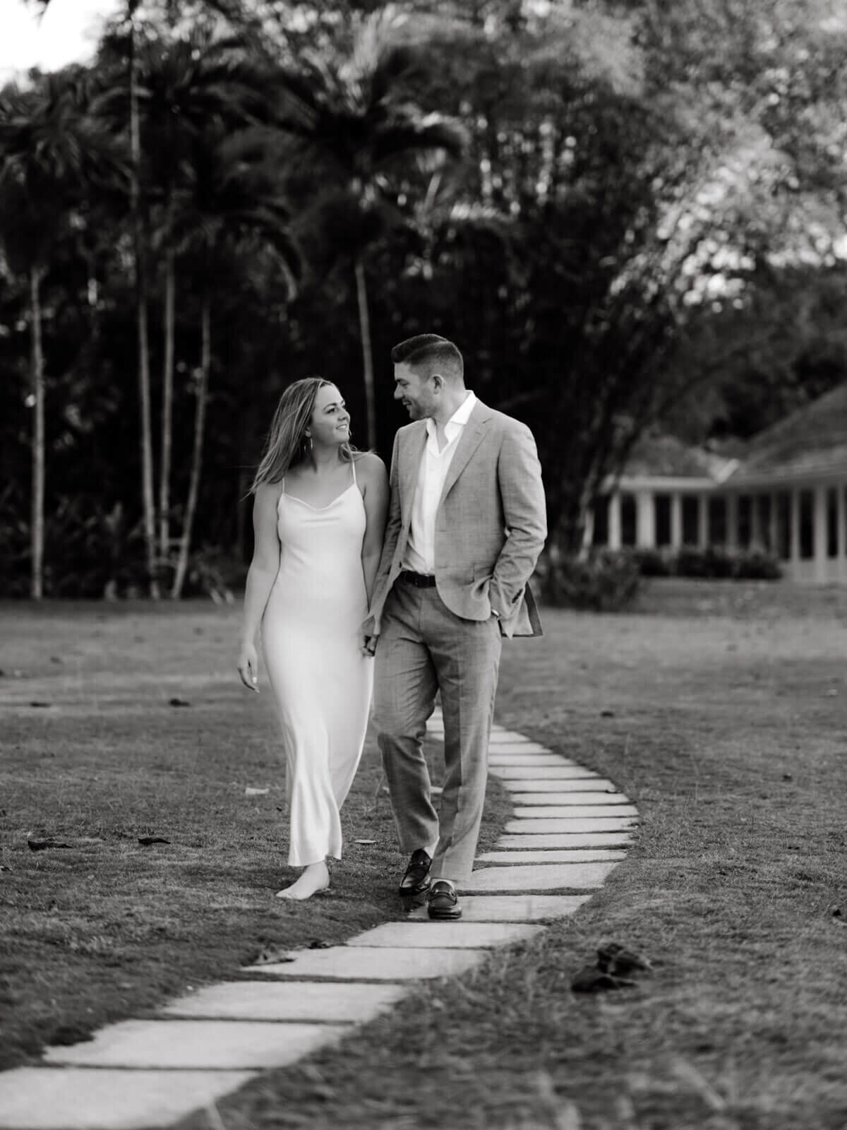 Black and white photo of the engaged couple walking in a trail path in the garden on Round Hill Hotel and Villas, Jamaica.