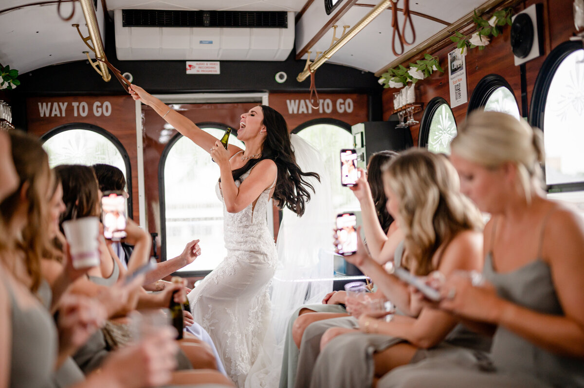 A bride uses a bottle as a microphone  while dancing on a Trolley