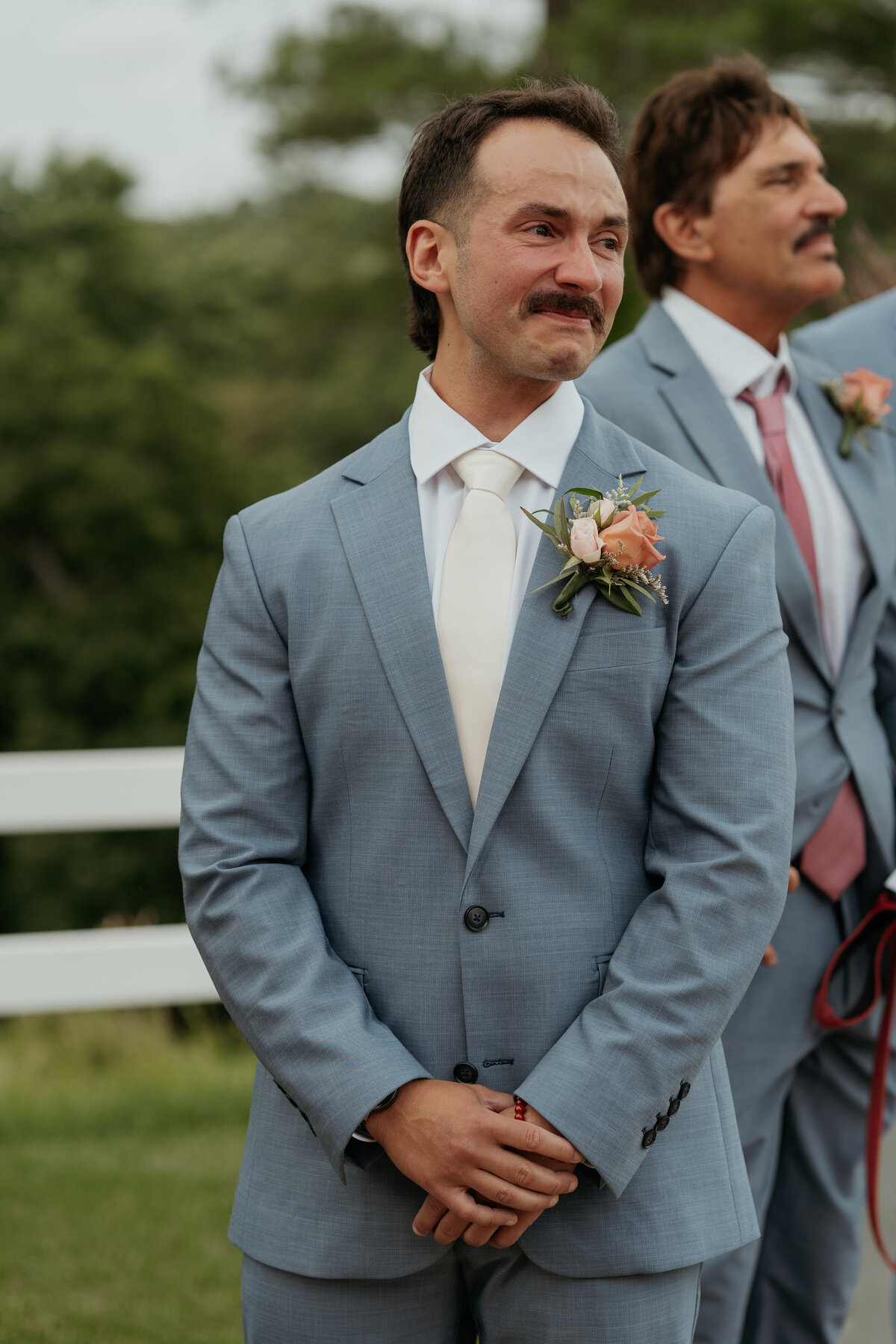 Emotional groom in a light blue suit and white tie with a peach boutonniere tears up as he waits at the altar, capturing a heartfelt moment during the wedding ceremony. Ideal for couples seeking a documentary-style wedding photographer to capture genuine and emotional reactions.