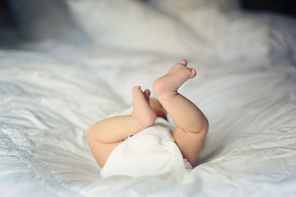 newborn laying on back with feet up in the air