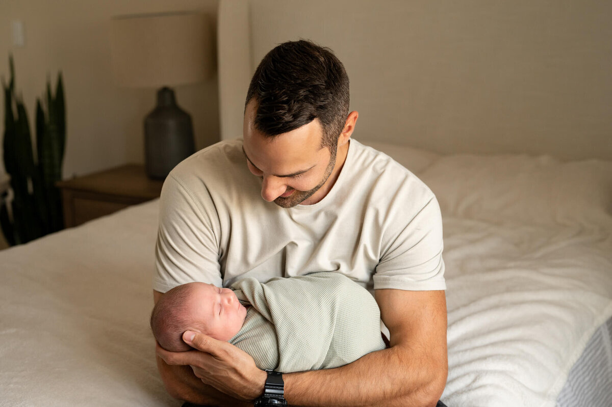 Dad holding newborn and looking down at him