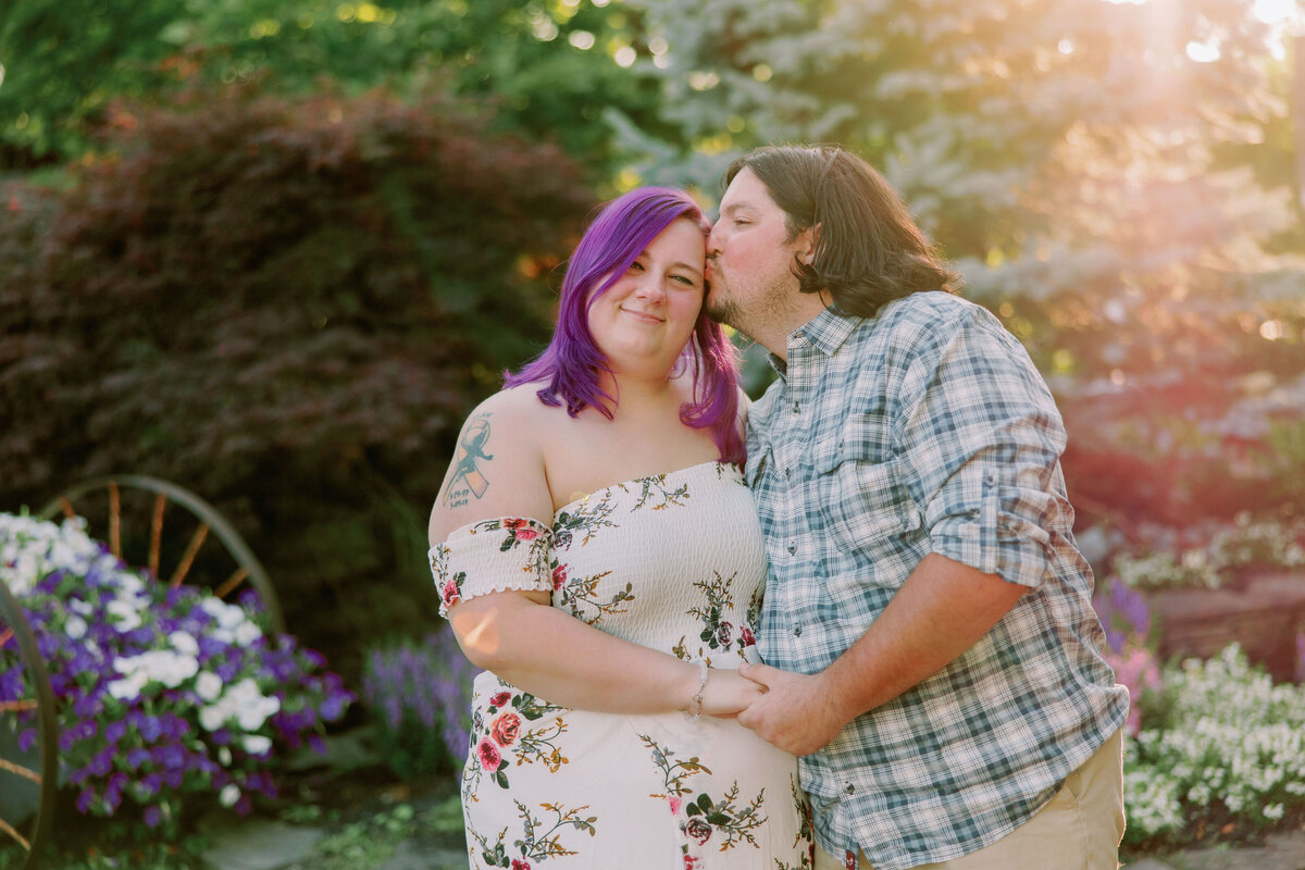 A person kissing their partner's temple as they hold hands 