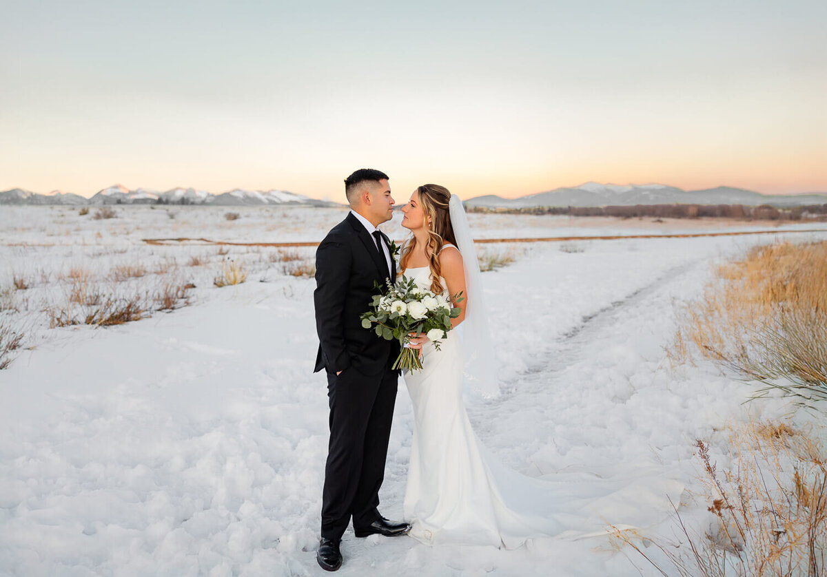 Bride and groom intimately looking at each other in the snow. Captured by Michelle Betz Photography, a Colorado Springs wedding photographer