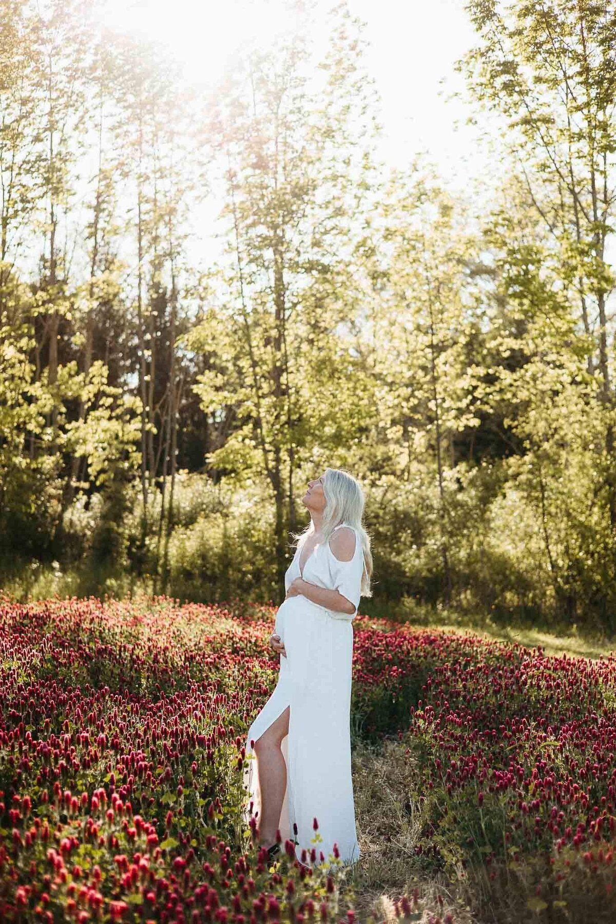 A pregnant woman stands peacefully in a vibrant field at Rogish Farm, captured during a Cleveland maternity photography session in beautiful natural light.