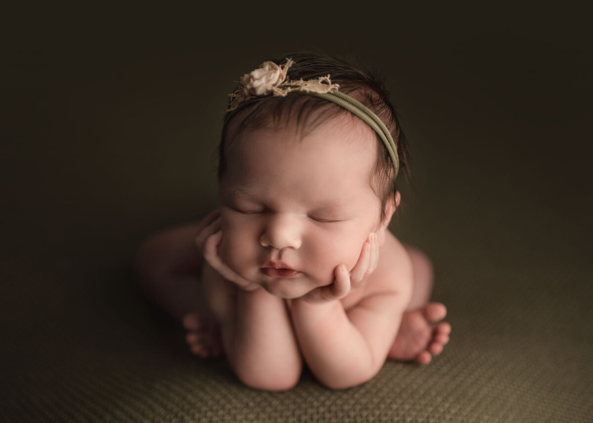 Baby sleeping in froggy pose holding up head on olive green posing blanket. Baby wearing olive green and blush headband