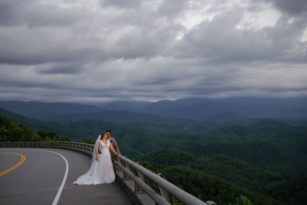 Smoky Mountain elopement photos with bride adn groom embracing on the road while leaning against the outlooks barrier