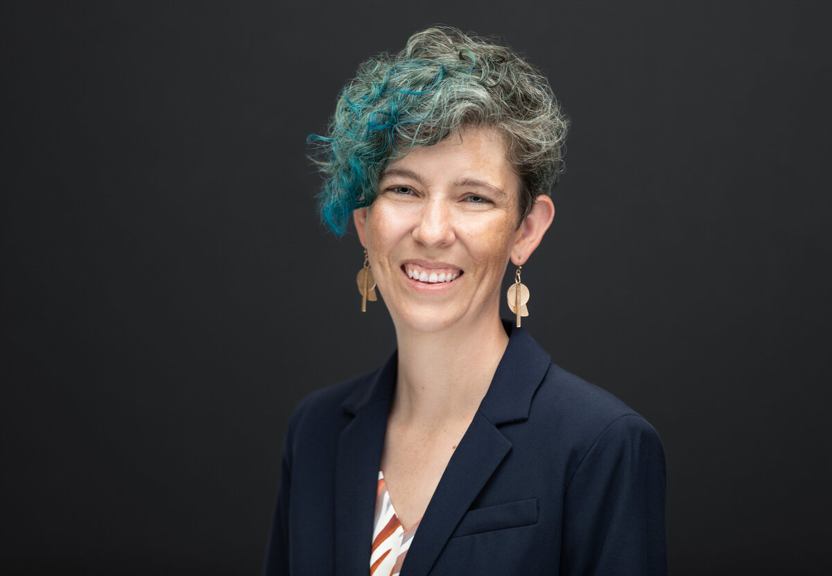 A woman with short blue and green hair and a black blazer poses for a professional headshot for Janel Lee Photography studios Cincinnati Ohio