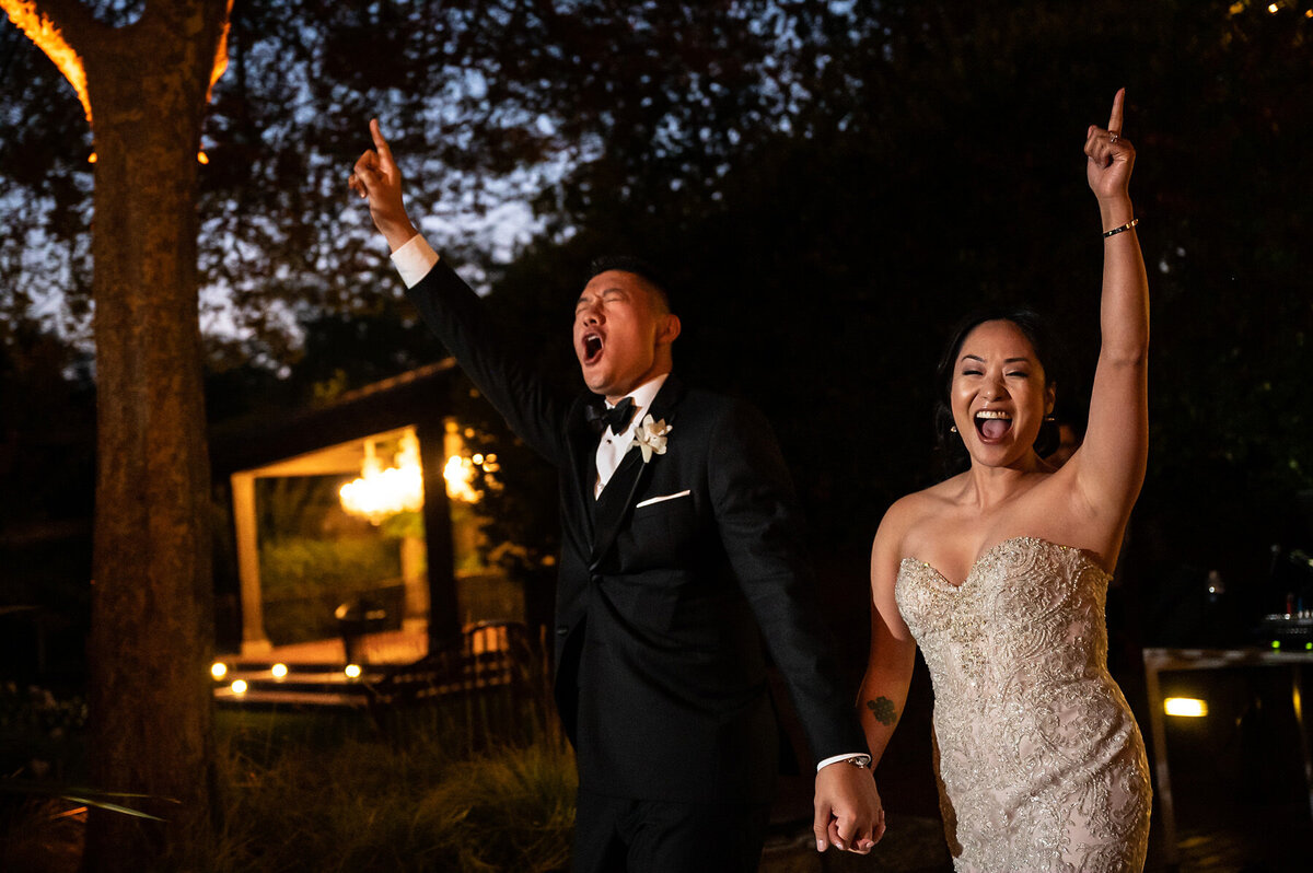 San Francisco Bay Area wedding photographer captures joyful bride and groom celebration moment with authentic laughter and raised hands at Estate Yountville in Napa Valley