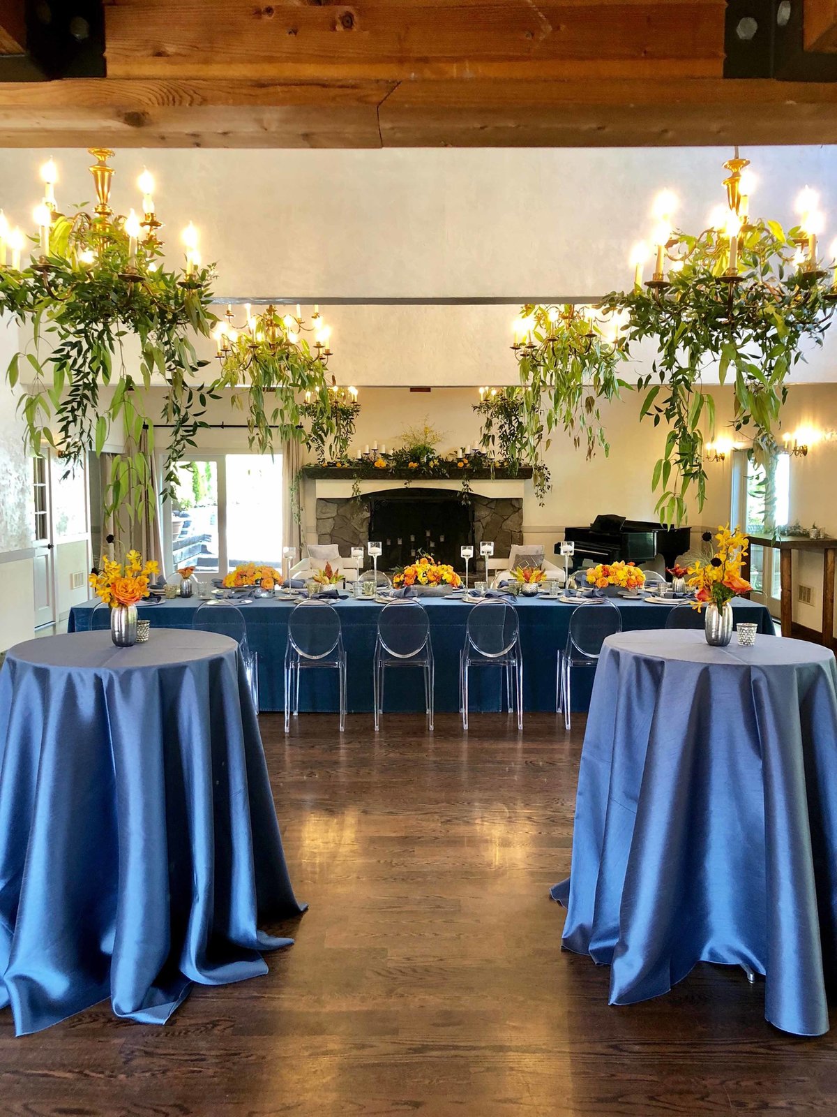 elegant company dinner party at Chateau lill with blue linens and orange flower centerpieces and greenery chandelier