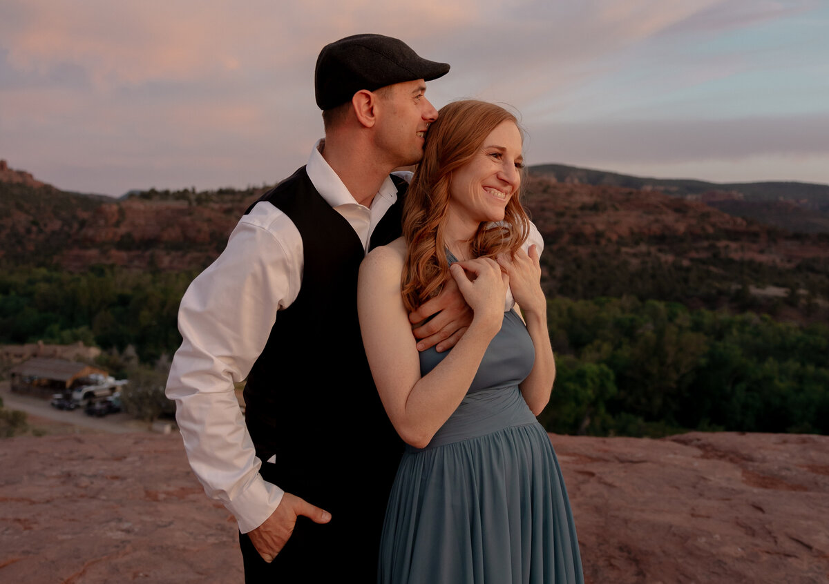 Couple standing against red rock backdrop during Sedona engagement session