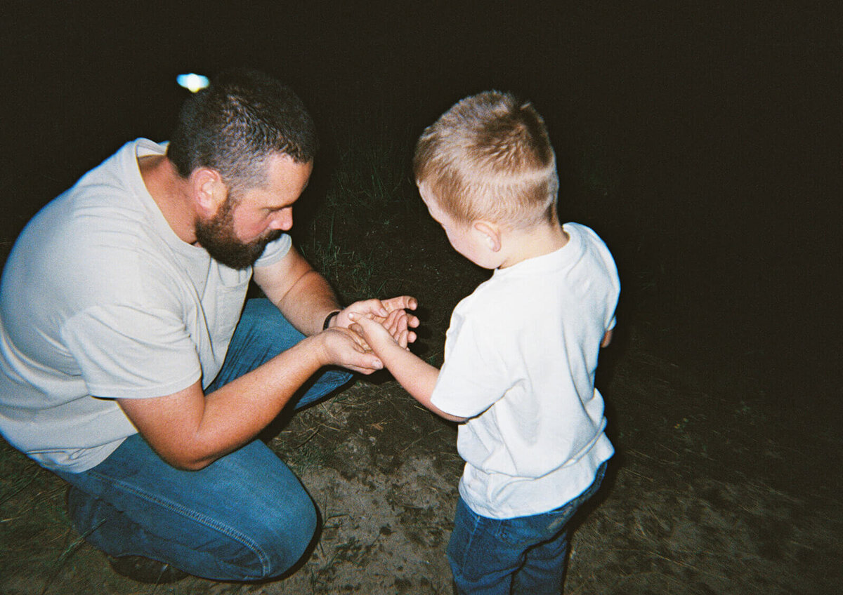 A boy shows something in his hand to his father.