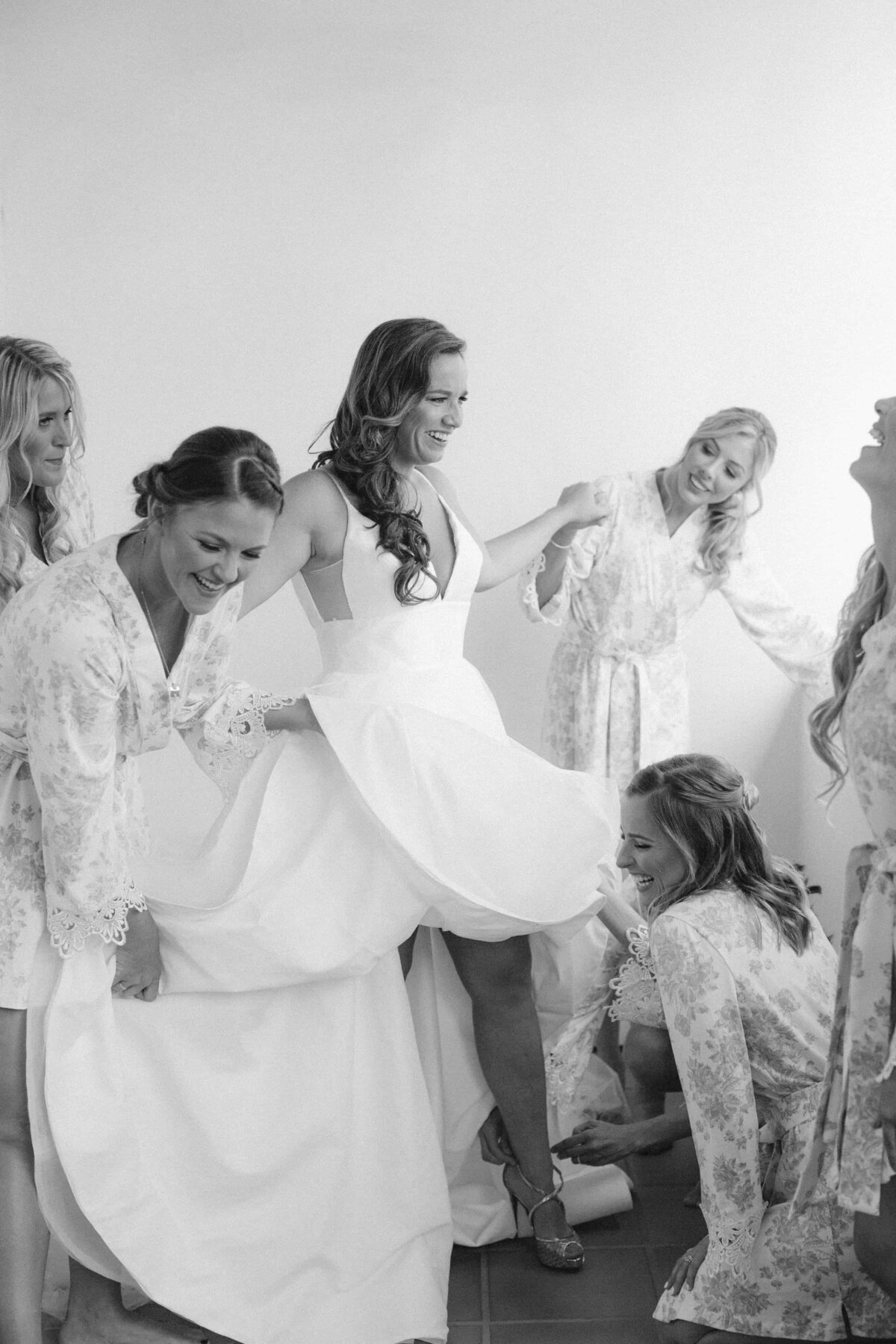 Bride getting dressed with help from the bridal party