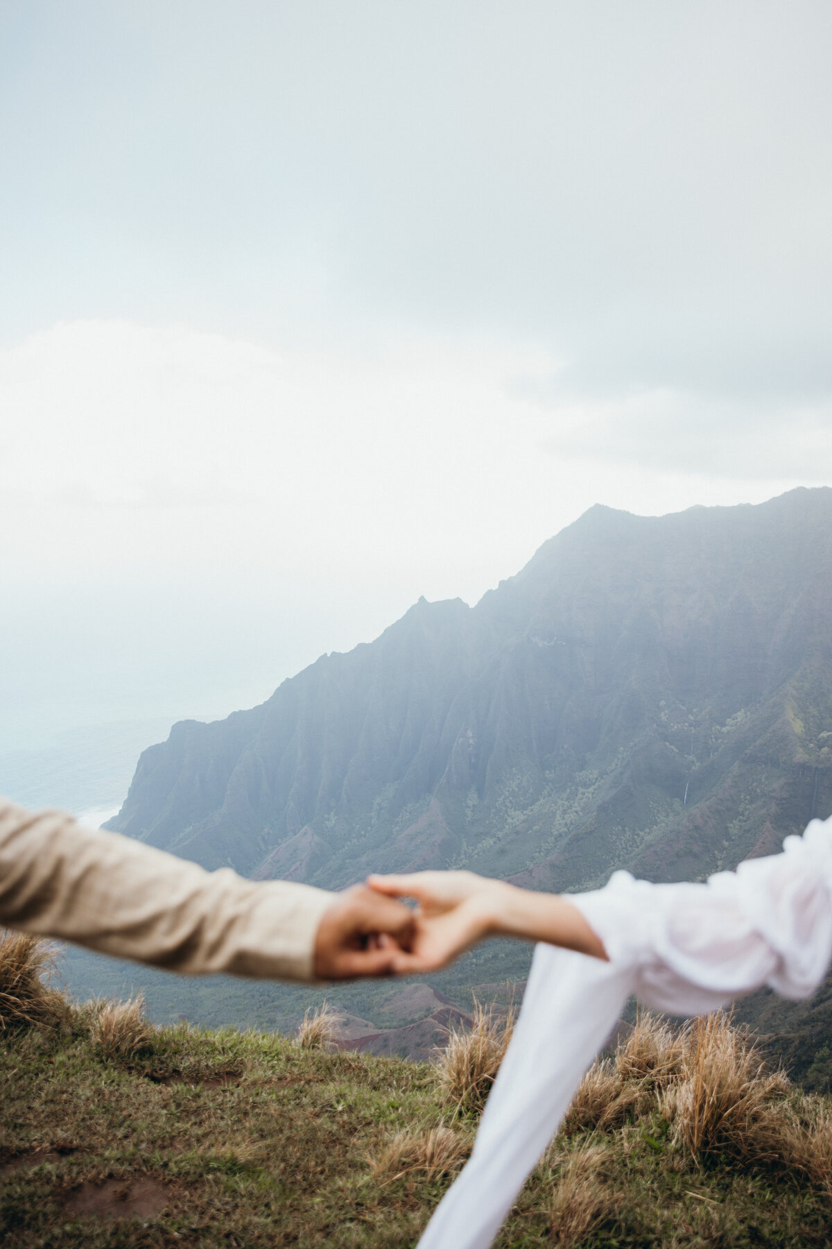 Maui Wedding Photographer captures bride and groom holding hands over cliff