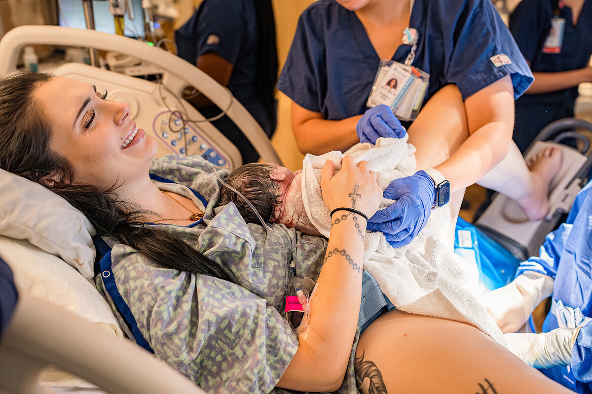 Newborn baby put onto mother's chest shortly after birth at MUSC, surrounded by gentle hands during a midwife-assisted delivery