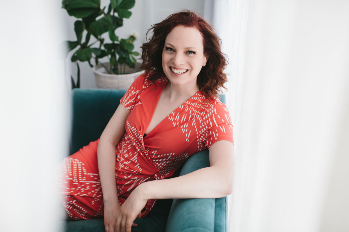 older business woman leaning against couch smiling at the camera