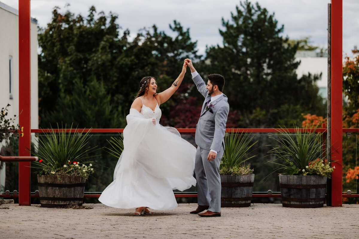 A bride and groom dancing in front of barrels at Wild Onion Brewery.