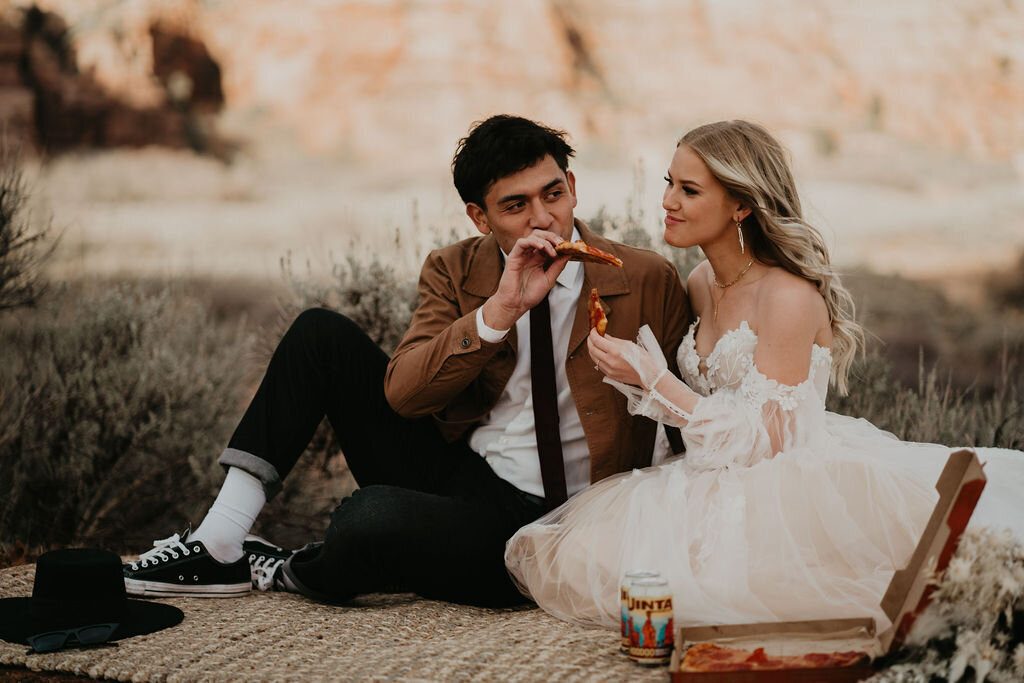 Couple sharing a slice of pizza and beer after their Zion elopement
