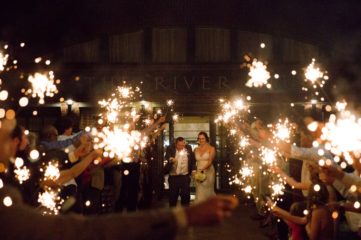 Bride and groom running through a sparkler sendoff tunnel photographed by Kansas City wedding photographer, Caia Grace