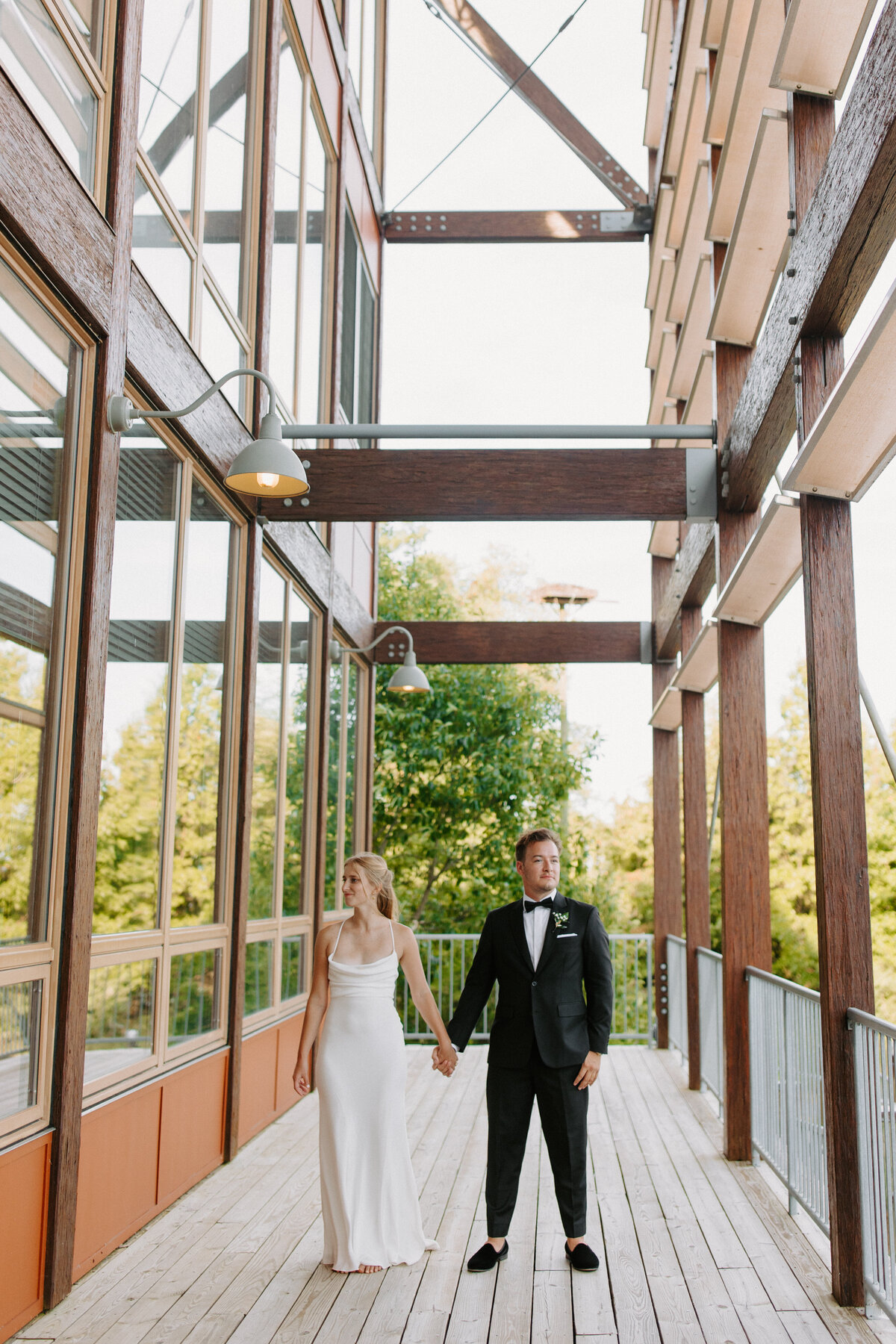 bride and groom holding hands and looking in opposite directions