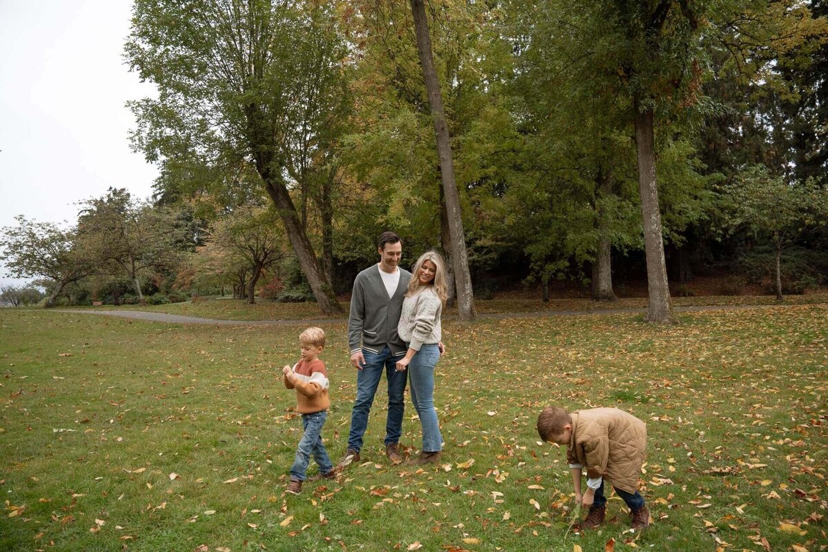 a male and a female playing with their two small boys at a park in fall