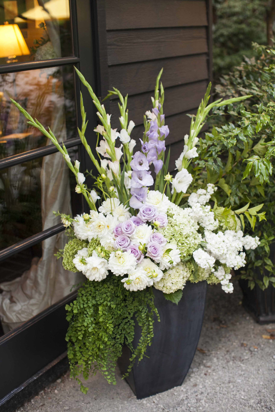 large black planter with purple and white roses, gladiolas, and ferns