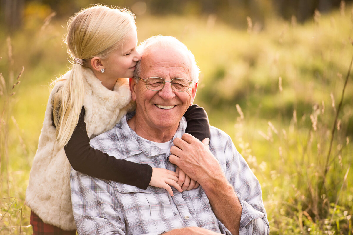 a photo of a little girl hugging and kissing her grandfather taken by Ottawa Family Photographer JEMMAN Photography