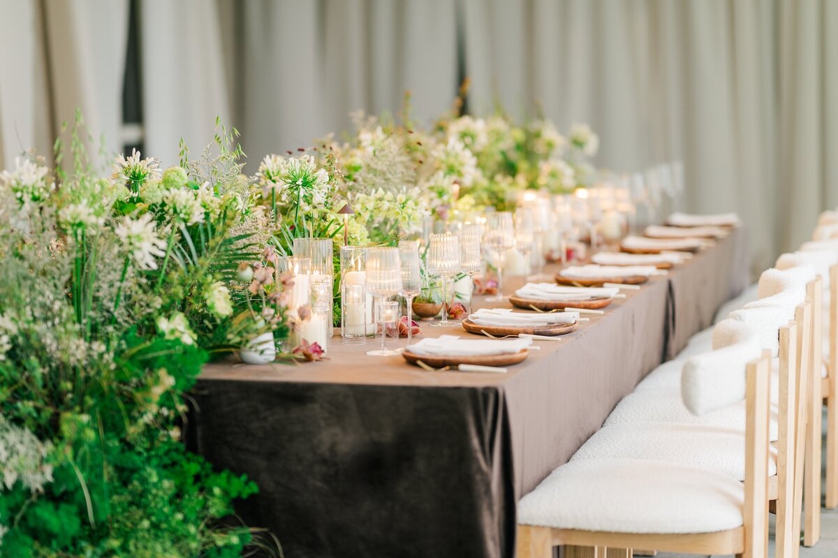 A table setting with a brown tablecloth, a cascading floral arrangement, and plates and candles on the outdoor terrace at Glen Manor House. 