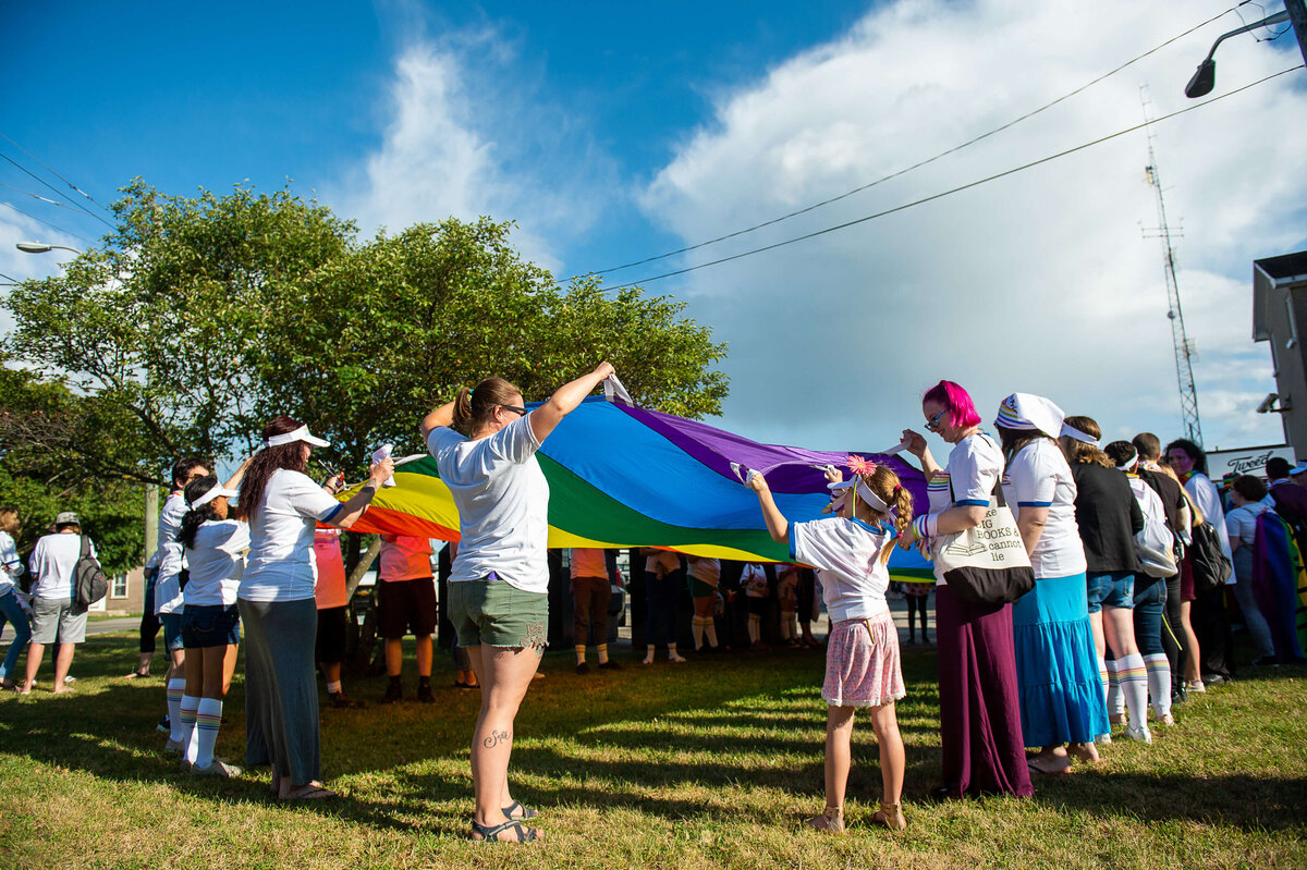 Ottawa event photography showing pride marches waving a pride parachute. Captured by JEMMAN Photography COMMERCIAL