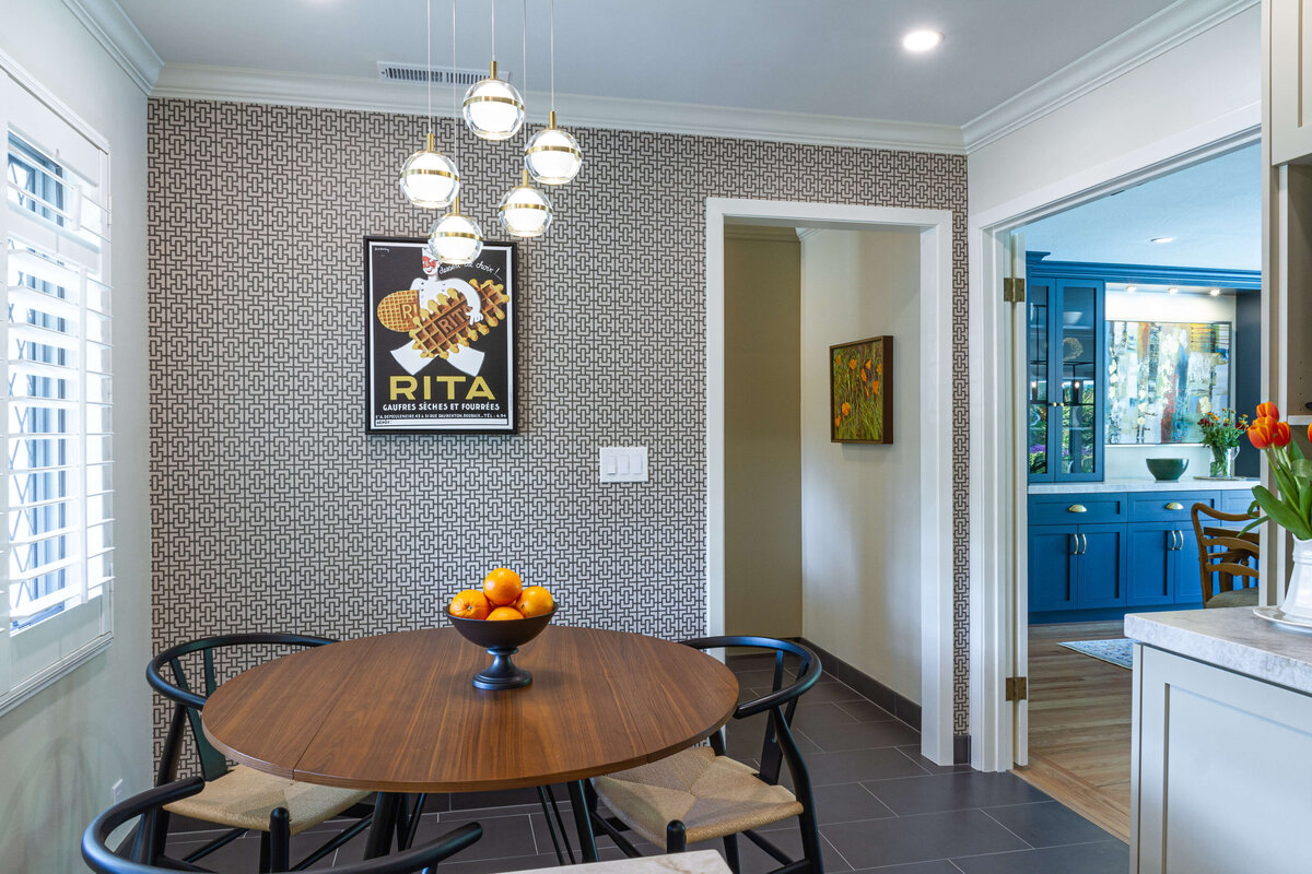 a dining table with chairs and a bowl of oranges