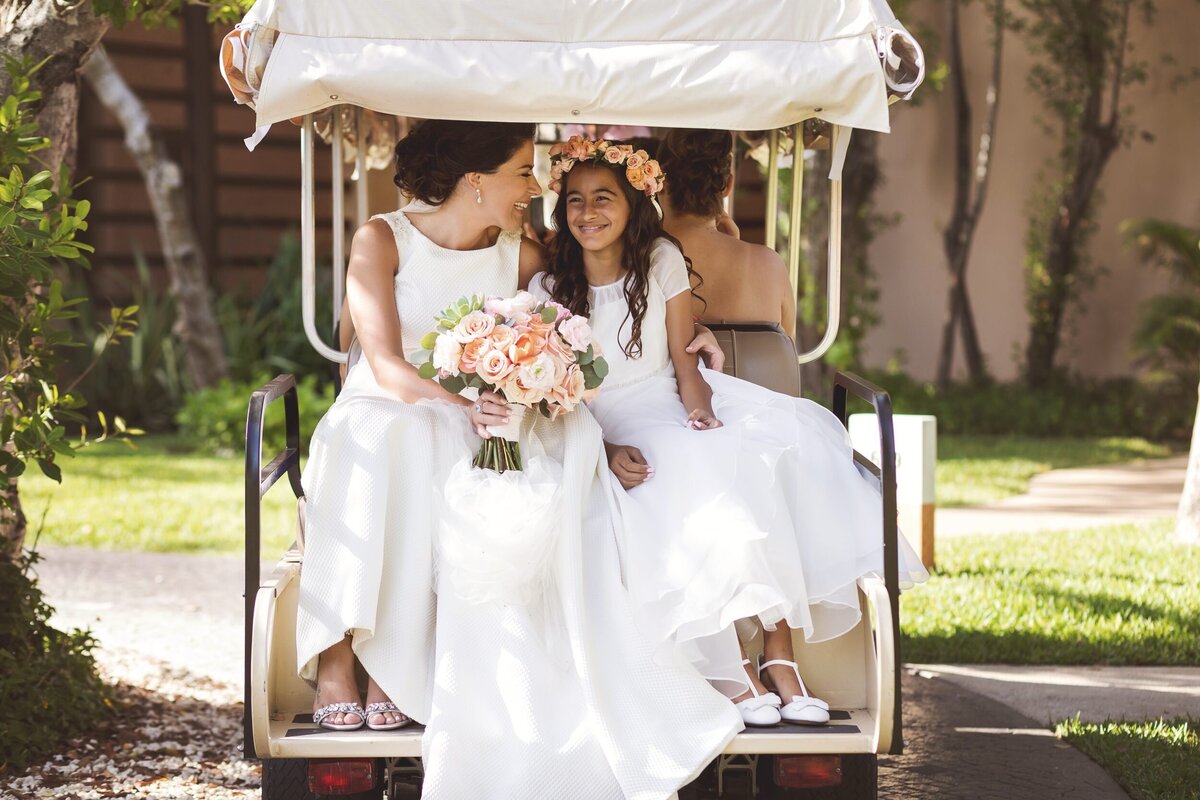 Bride and flower girl in golf cart going to ceremony at Banyantree Myakoba