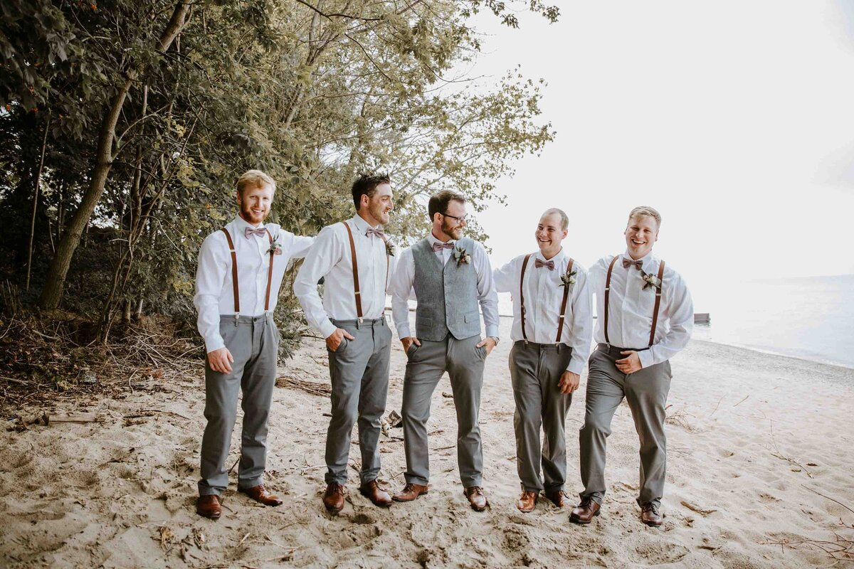 Groom and Groomsmen stand in a line and pose casually on an Exeter, Ontario beach.