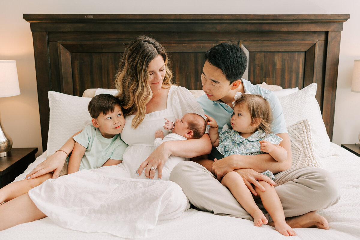 Family of five sharing a laugh as the only daughter is playing with the babies hair.