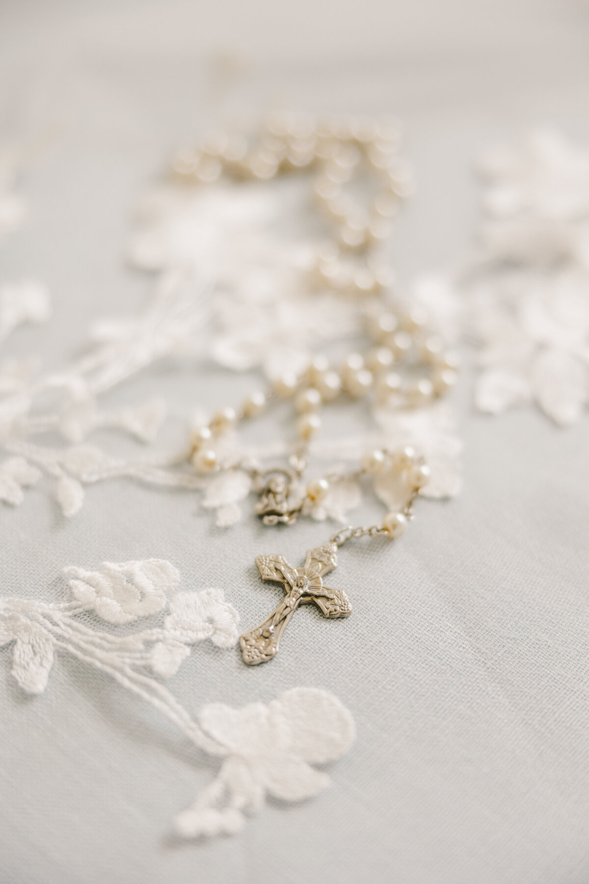 Rosary beads laying on top of a lace veil