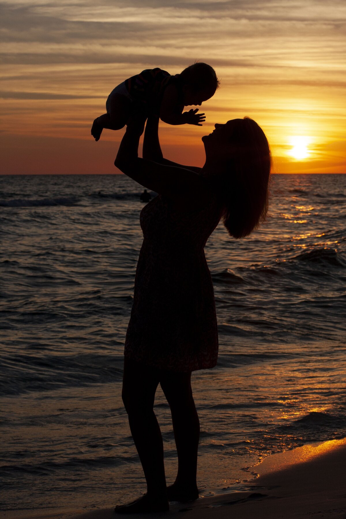 mom holding baby on the beach