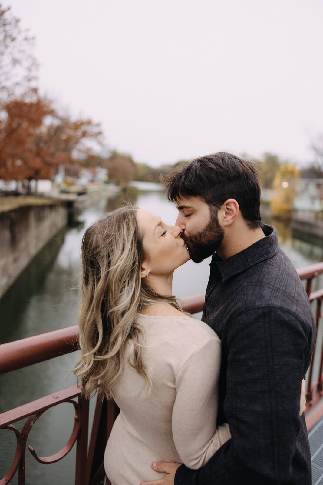 Couple kissing in front of river at at Finger Lakes maternity session