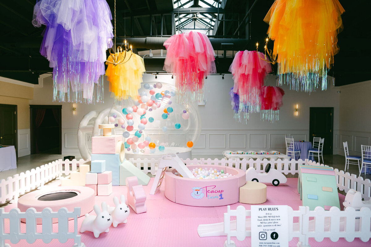 Colorful bounce house at a children’s birthday party venue, surrounded by vibrant balloons, playful decorations, and festive table settings, creating a fun and lively atmosphere