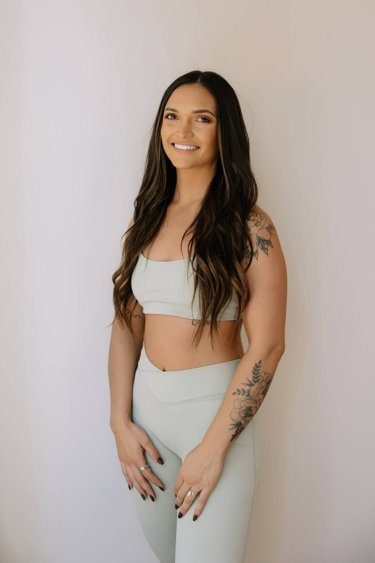 A woman in sage green workout clothes poses for a photo.