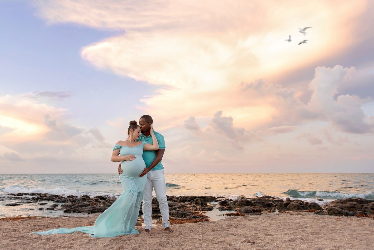 South Florida beach maternity pictures during a peaceful sunset of a couple in blue.