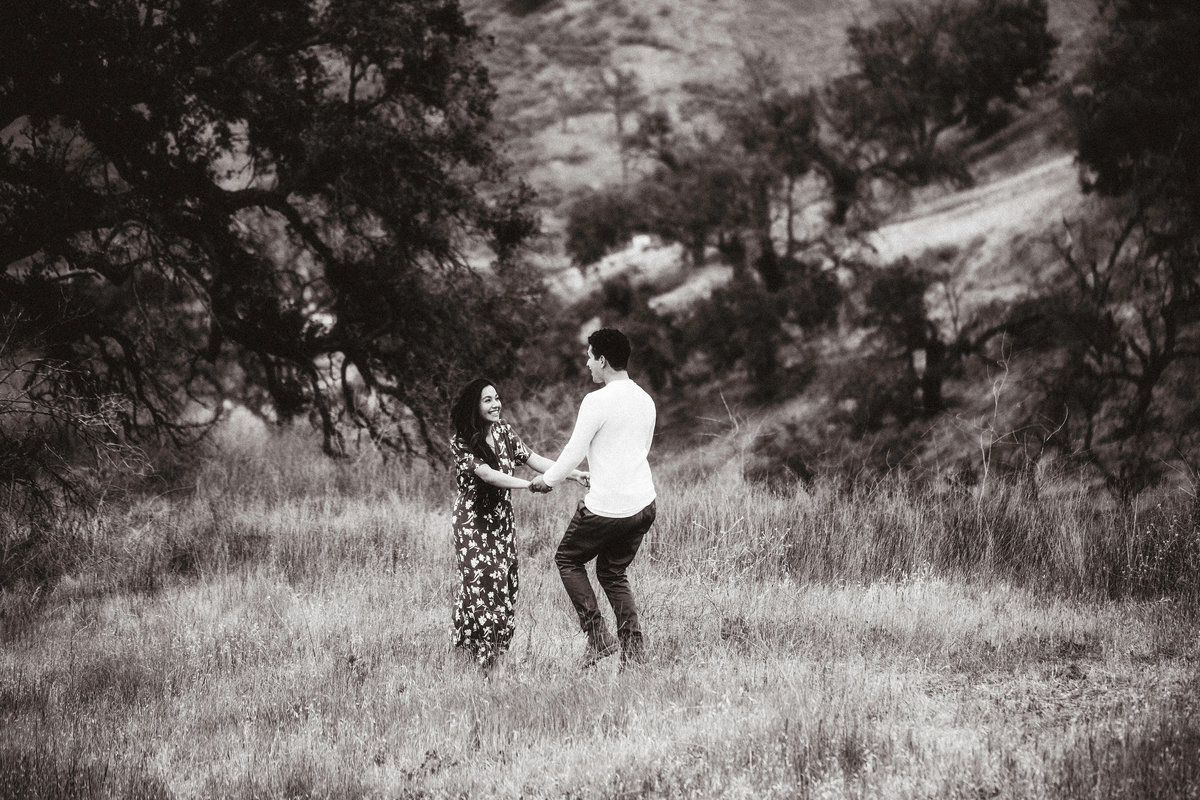Engagement Photograph Of  Man And Woman Holding Hands In The Middle Of a Meadow Los Angeles