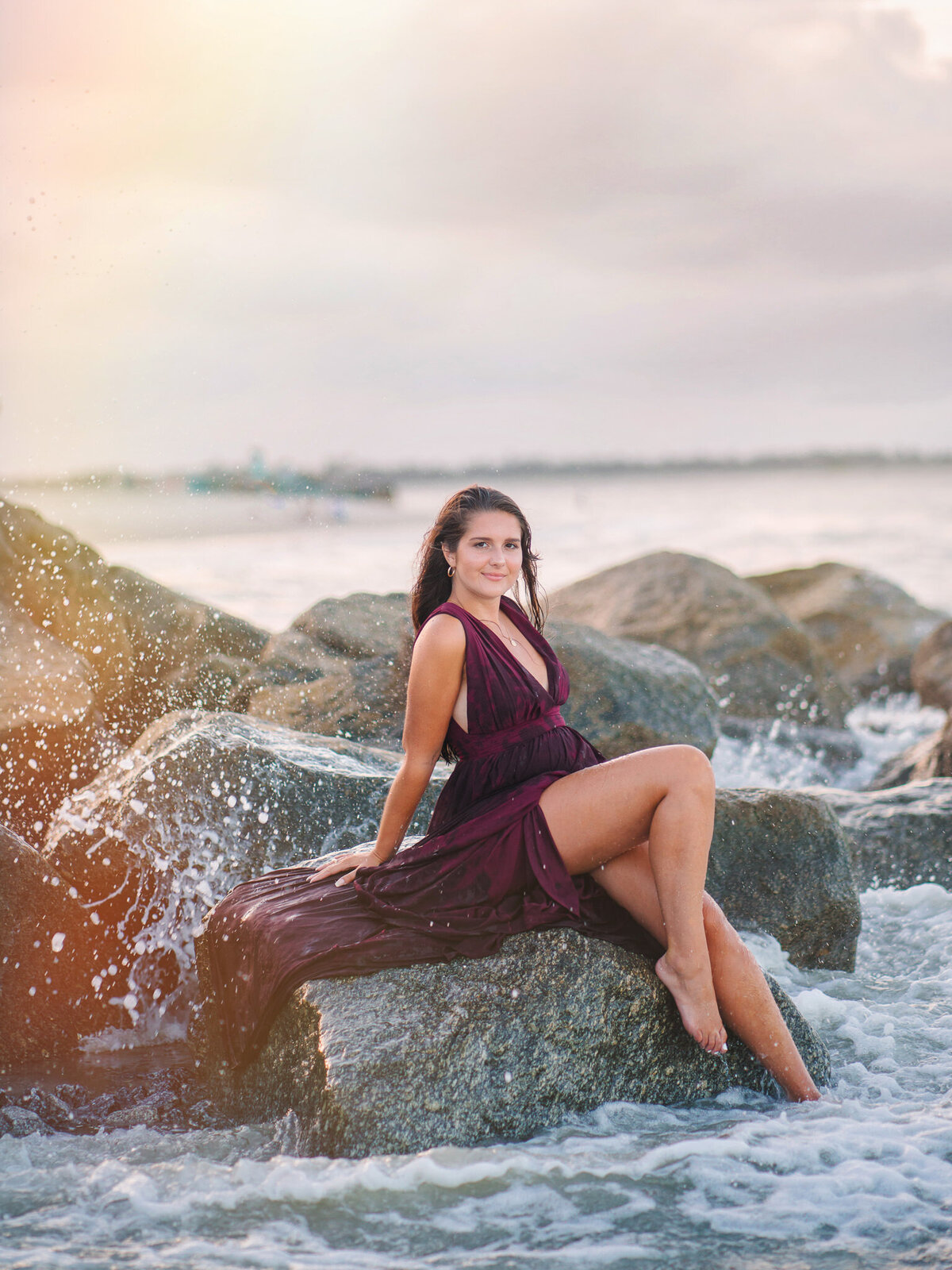 Teen girl with flowing dress posing on hillside at golden hour for senior photos in Folly Beach