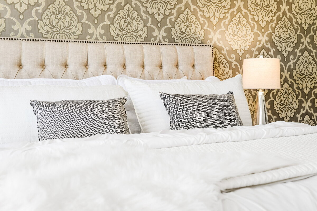 Tufted bed with pillows and wallpaper wall