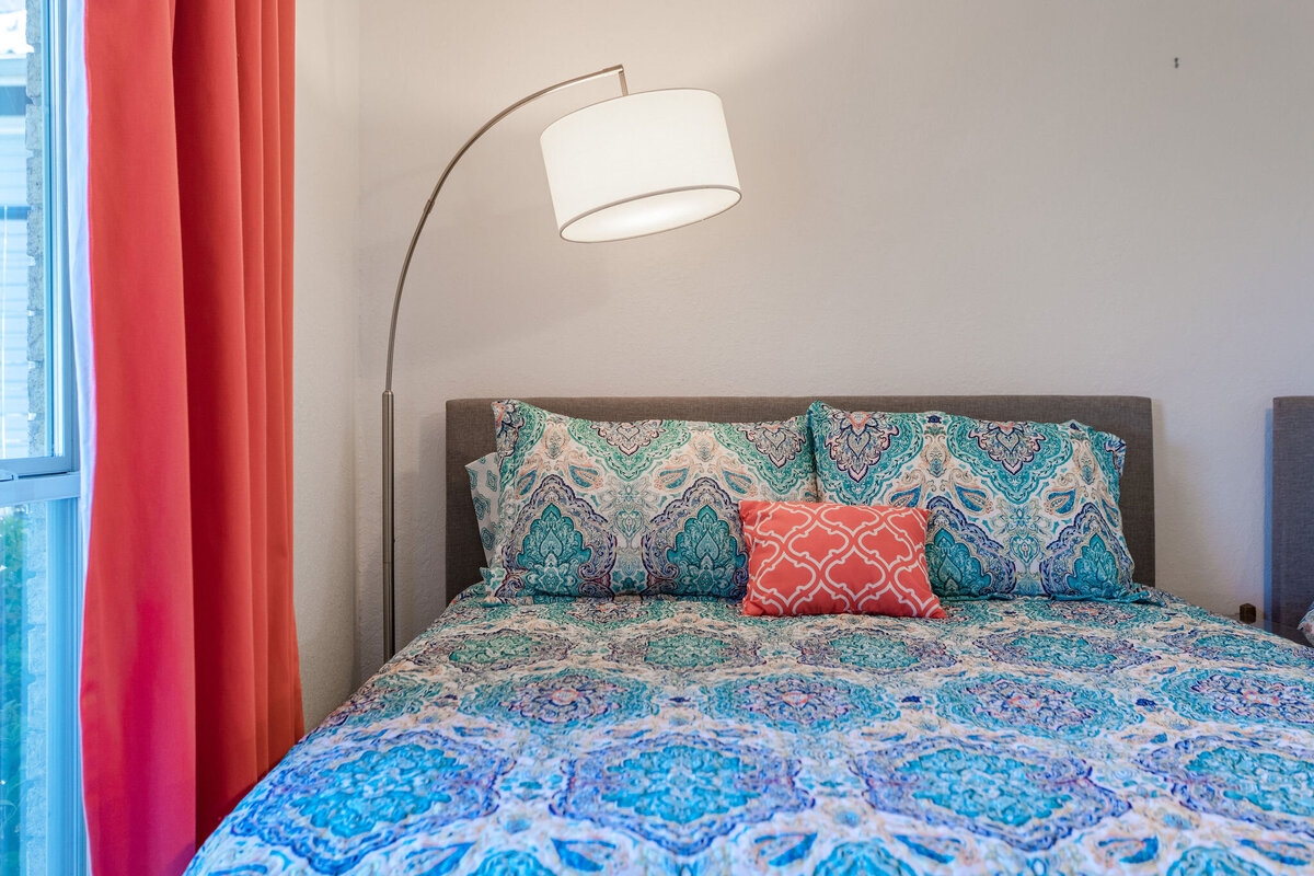 Bedroom with comfortable bedding and reading lamp in this 2-bedroom, 2-bathroom lakeside vacation rental home for 6 guests on Tradinghouse Lake with privacy access to a fishing dock and boat launch pad, ping pong table, gazebo, free wifi and free parking in Waco, TX.