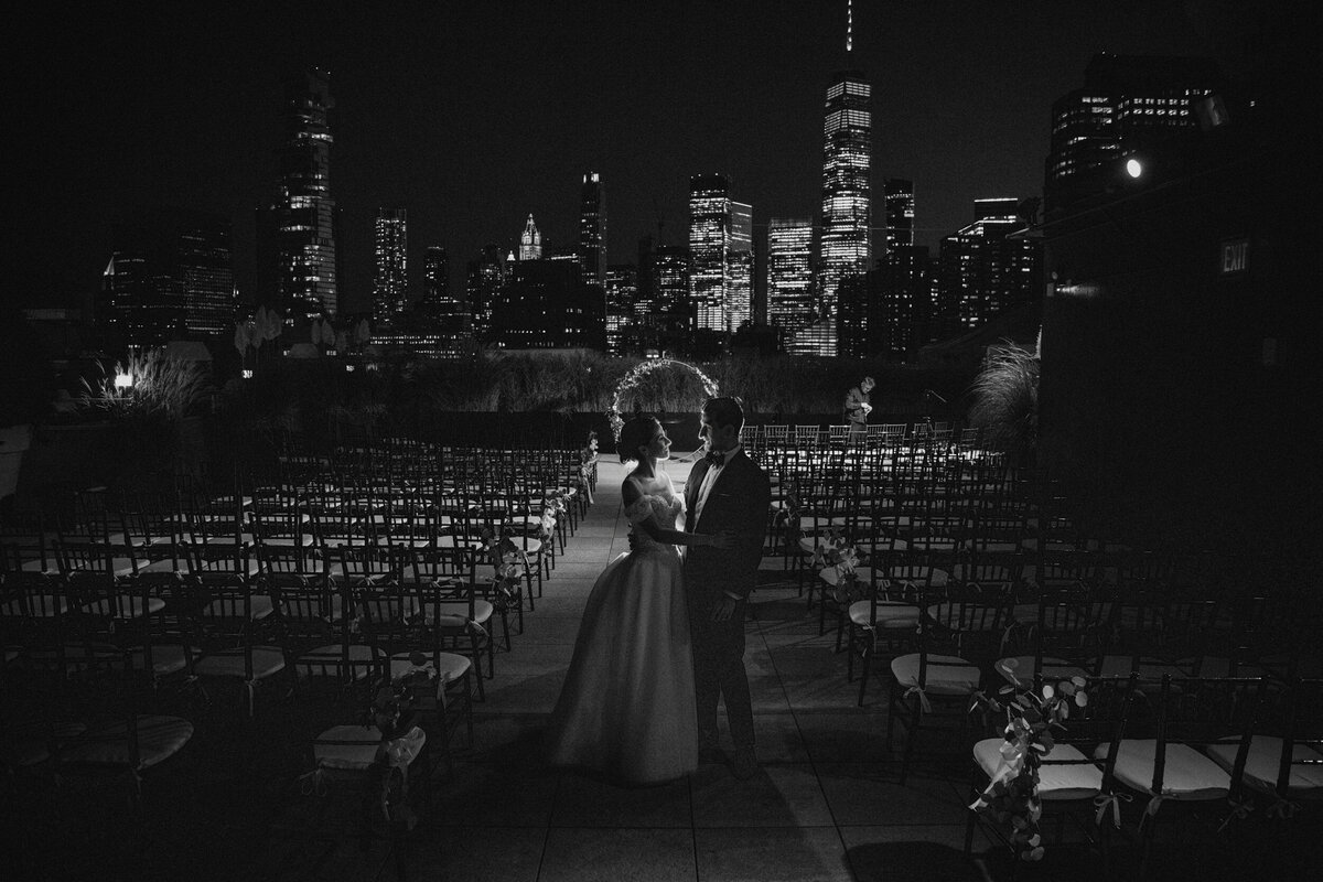 A couple poses for skyline night photos at a Tribeca Rooftop wedding in Manhattan