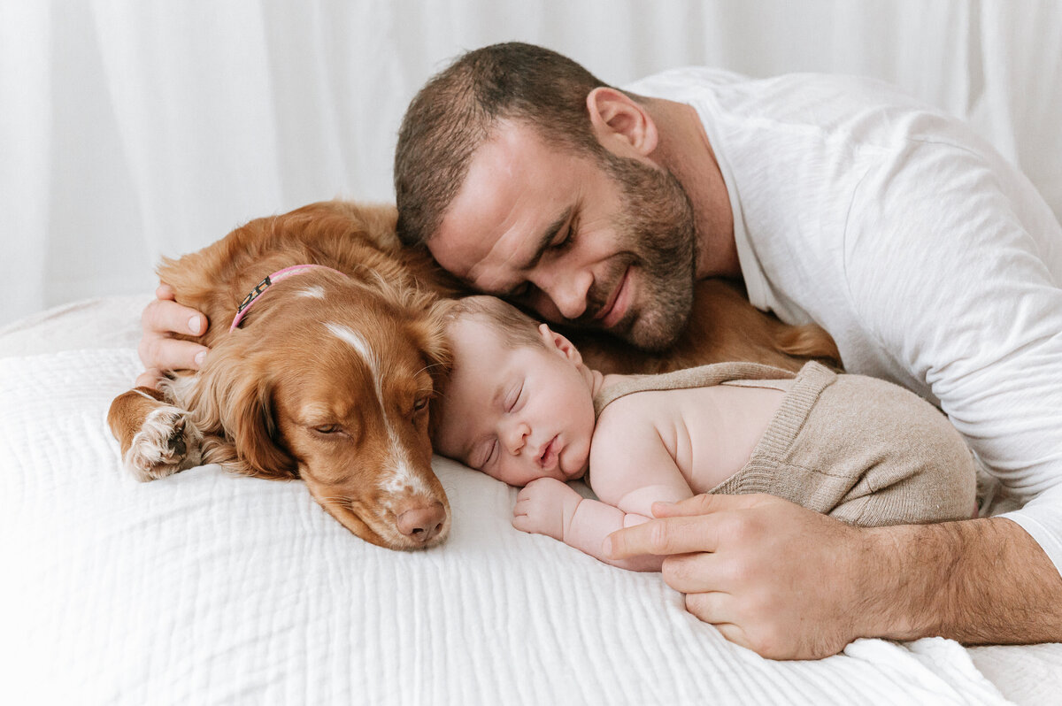 Rugby player Dad cuddles his dog and newborn during a photoshoot