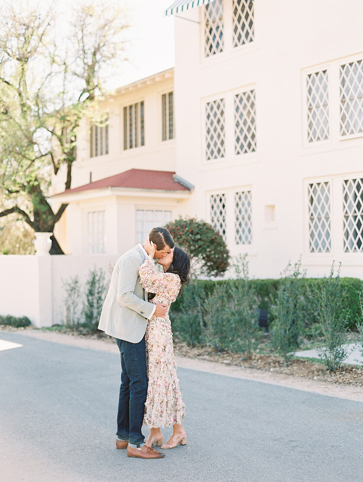 stylish couple kisses in front of Laguna Gloria's Driscoll Villa