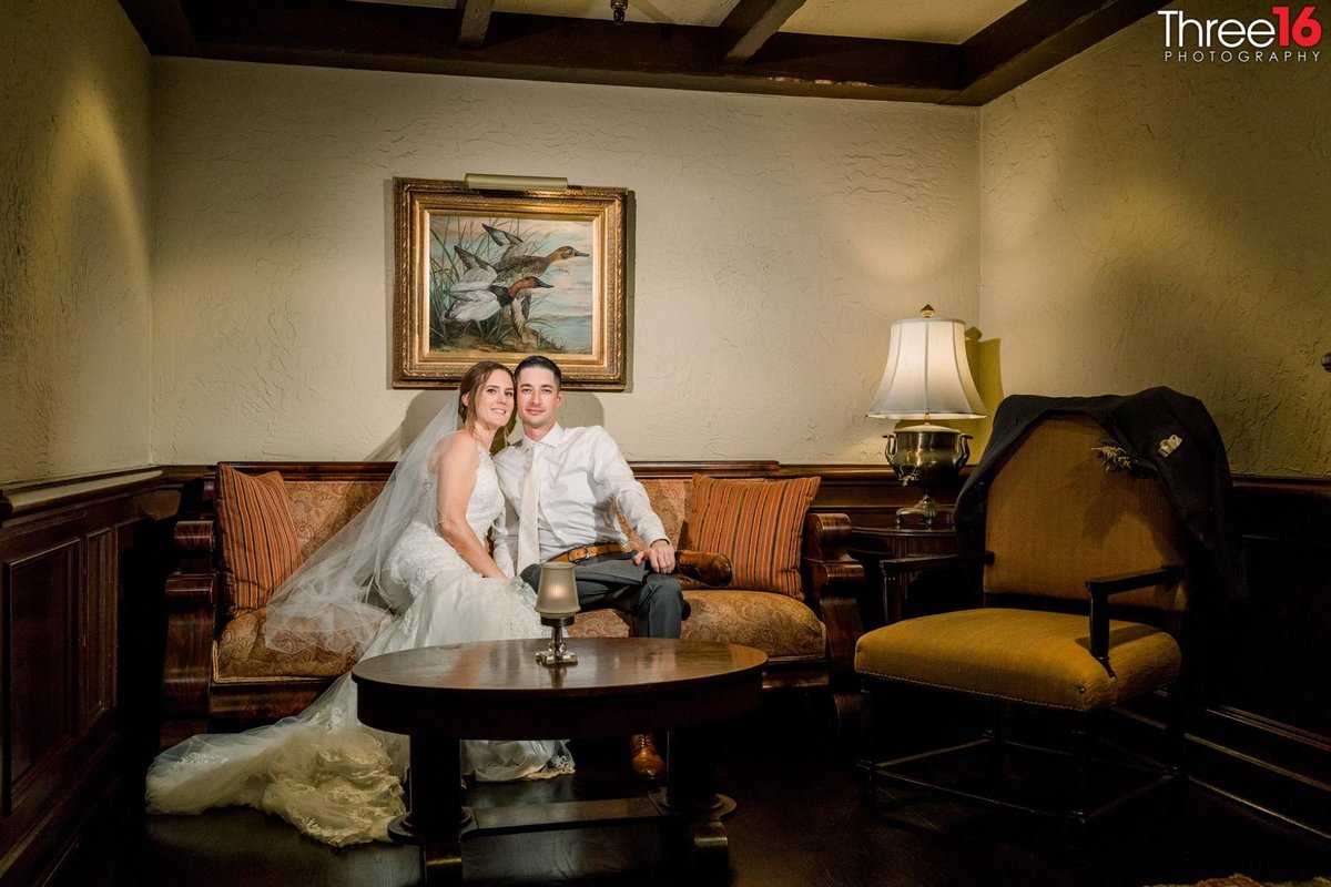 Bride and Groom sit on a couch in a vintage-style look