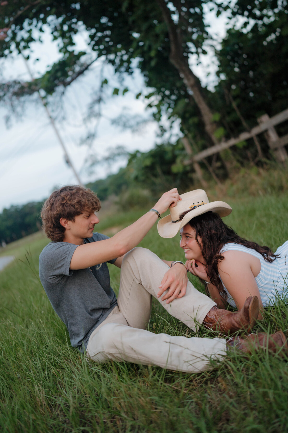 Playful couple laughing in a grassy Alabama field during a summer engagement session — EC Photography