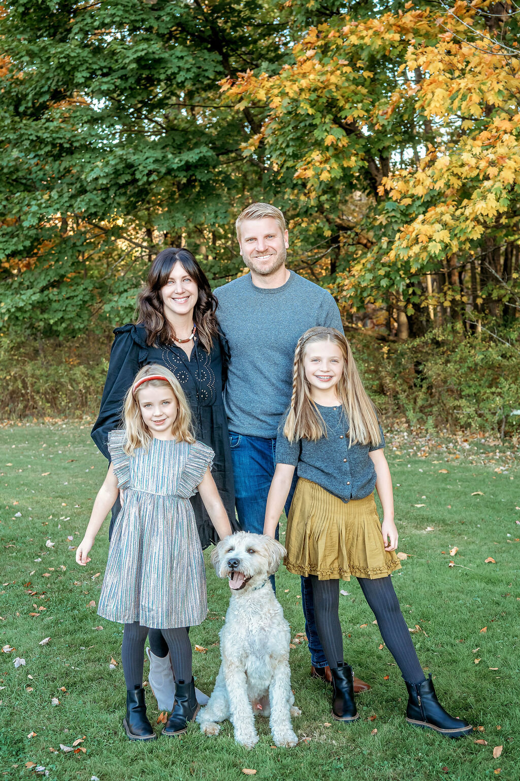 Connecticut family photographer captures family of four with their white poodle during autumn outdoor session in coordinated fall outfits