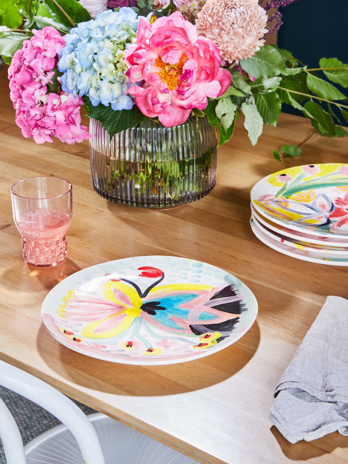 Close-up of vibrant floral arrangement and hand-painted plate – styled dining table by Melbourne interior stylist